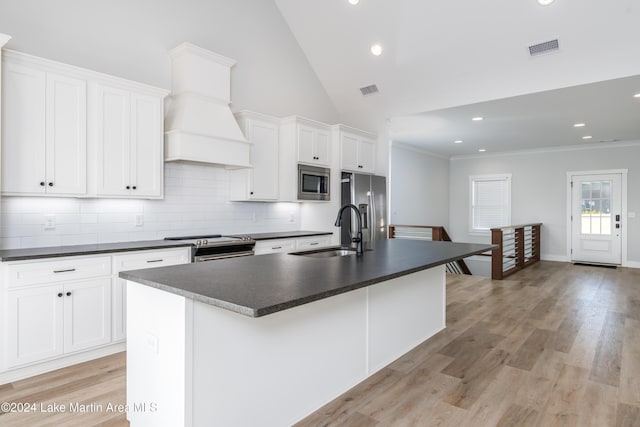 kitchen with stainless steel appliances, sink, light hardwood / wood-style flooring, white cabinets, and an island with sink