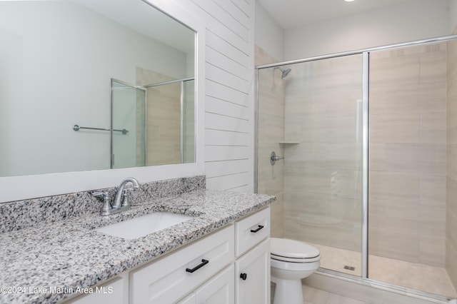 bathroom featuring vanity, toilet, and a shower with shower door