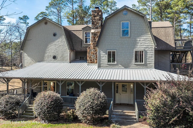 view of front facade featuring a porch, a shingled roof, and a gambrel roof