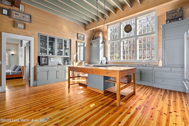 interior space featuring beamed ceiling, wooden walls, and light wood-type flooring