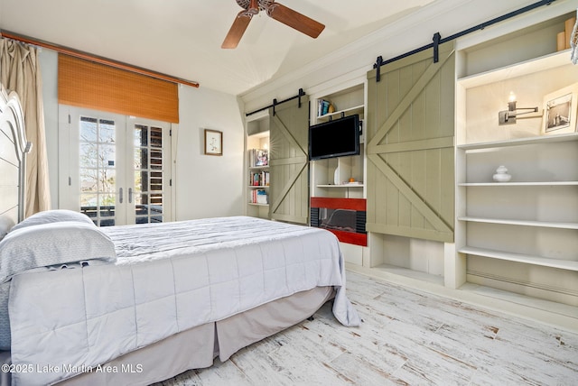 bedroom featuring crown molding, access to exterior, wood-type flooring, french doors, and a barn door