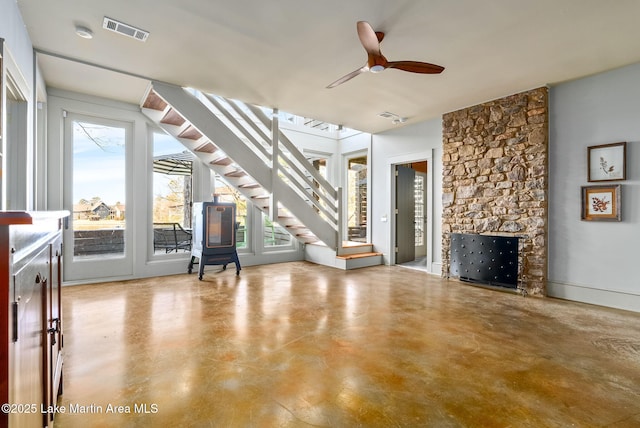 unfurnished living room with ceiling fan and a stone fireplace