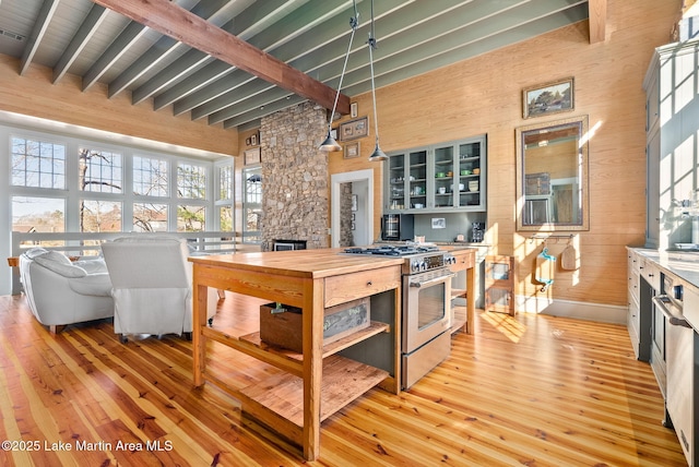 kitchen featuring gas range, light wood-type flooring, pendant lighting, and beam ceiling