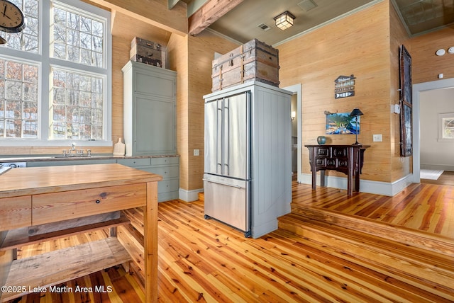 kitchen featuring sink, wooden walls, light hardwood / wood-style floors, and a high ceiling