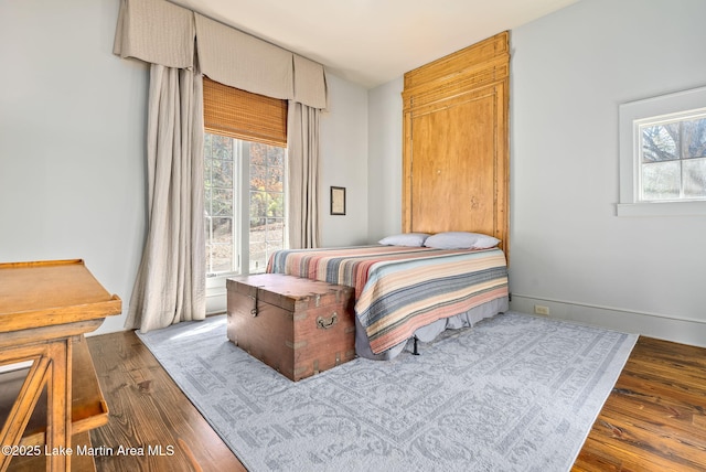 bedroom with multiple windows and dark hardwood / wood-style floors