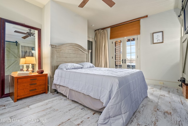 bedroom with access to exterior, light hardwood / wood-style flooring, a barn door, and ceiling fan