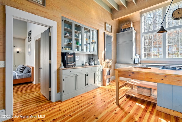 kitchen with wooden walls, beam ceiling, wood counters, and light wood-type flooring