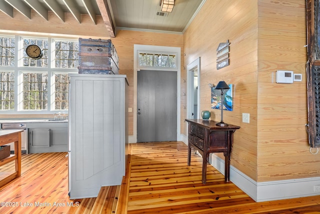 entryway with light wood-type flooring, a wealth of natural light, and wooden walls