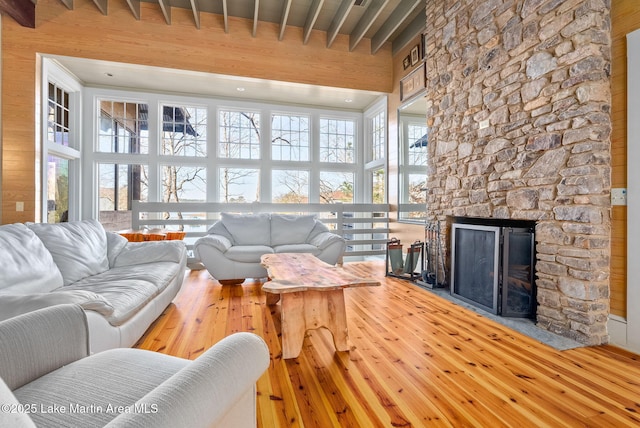 living room featuring a stone fireplace, hardwood / wood-style floors, and a high ceiling