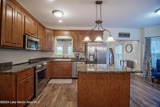 kitchen with a center island, stainless steel appliances, plenty of natural light, and hanging light fixtures