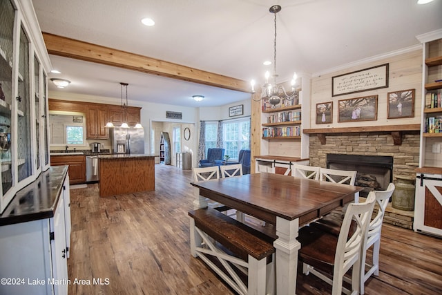 dining space featuring a fireplace, dark hardwood / wood-style floors, an inviting chandelier, and a healthy amount of sunlight