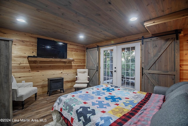 bedroom with a barn door, wooden walls, and hardwood / wood-style floors