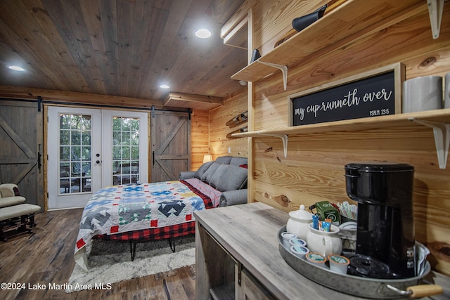 bedroom with access to outside, a barn door, wood walls, and dark wood-type flooring