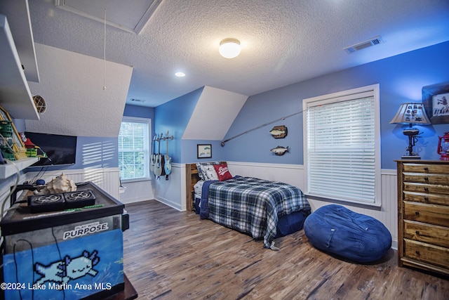 bedroom featuring vaulted ceiling, a textured ceiling, and hardwood / wood-style flooring