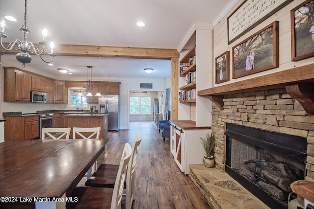 dining space with crown molding, a fireplace, dark wood-type flooring, and an inviting chandelier