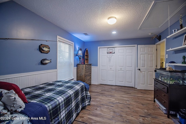 bedroom featuring lofted ceiling, a closet, a textured ceiling, and hardwood / wood-style flooring