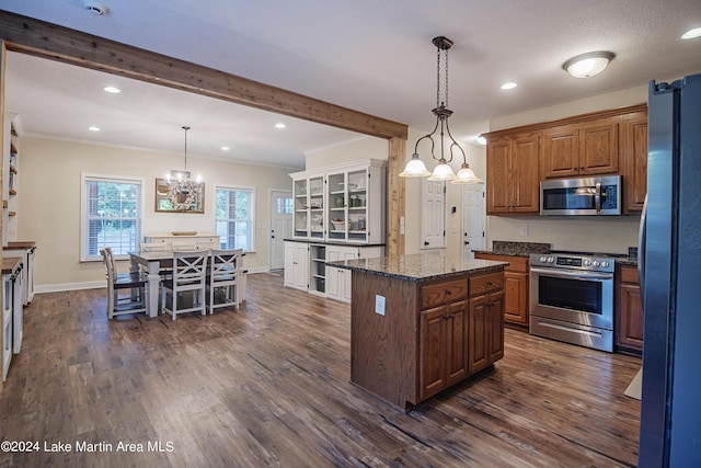 kitchen featuring appliances with stainless steel finishes, dark wood-type flooring, pendant lighting, dark stone countertops, and a kitchen island