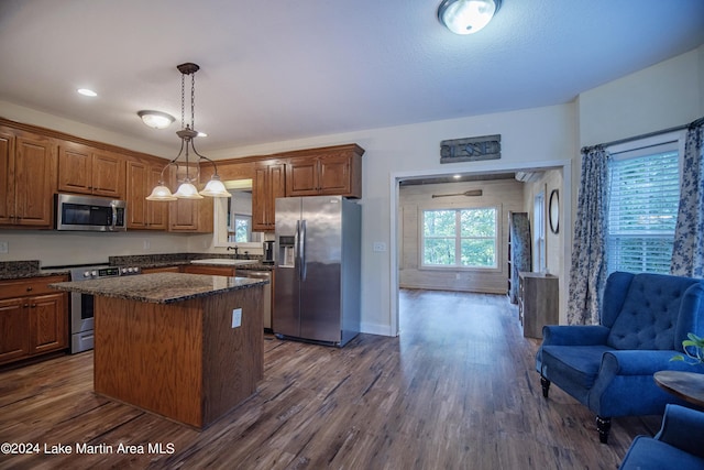 kitchen featuring a center island, dark wood-type flooring, sink, decorative light fixtures, and stainless steel appliances