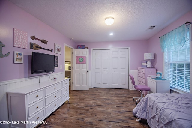 bedroom featuring a closet, dark wood-type flooring, and a textured ceiling