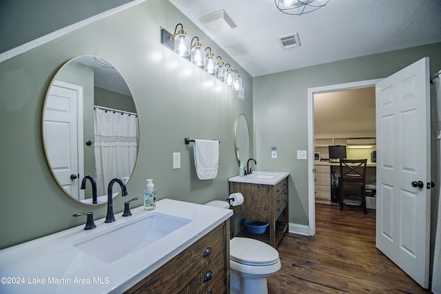 bathroom featuring wood-type flooring, vanity, a textured ceiling, and toilet