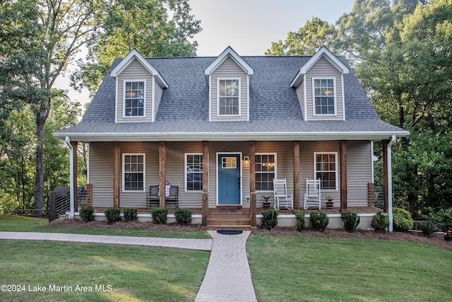 cape cod house with a front yard and covered porch