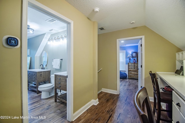 interior space with vanity, wood-type flooring, a textured ceiling, and toilet