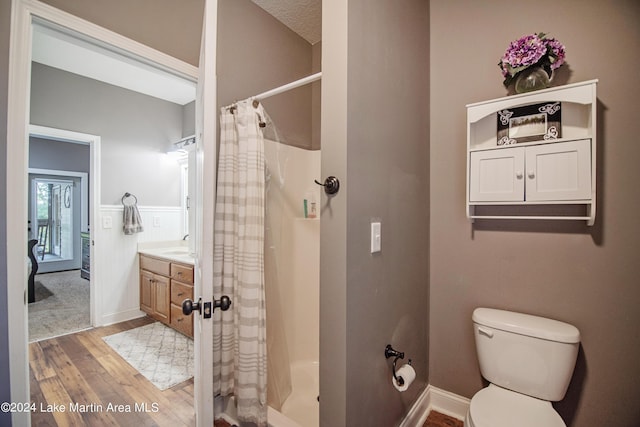 bathroom featuring hardwood / wood-style floors, vanity, curtained shower, and toilet