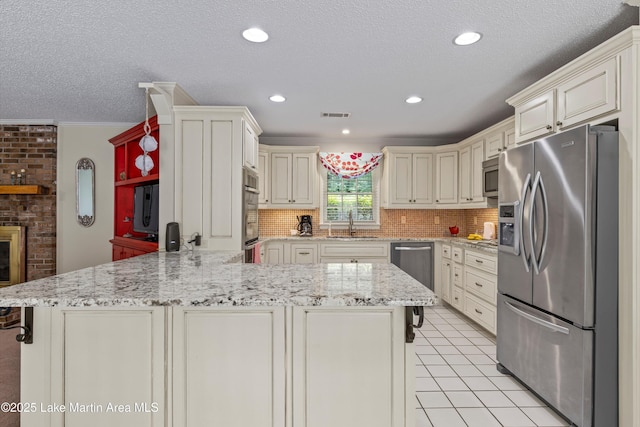 970 Raintree Dr, Alexander City, AL 35010 - kitchen featuring stainless steel appliances, a peninsula, backsplash, a textured ceiling, and light tile patterned flooring