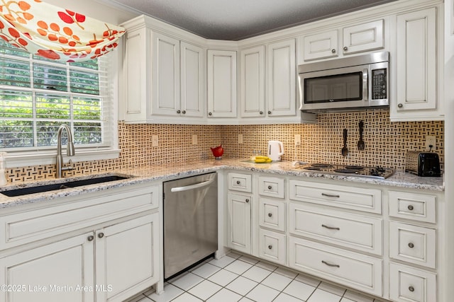 970 Raintree Dr, Alexander City, AL 35010 - kitchen featuring stainless steel appliances, light tile patterned floors, tasteful backsplash, and white cabinetry