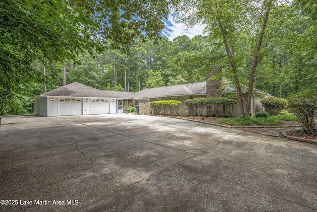 970 Raintree Dr, Alexander City, AL 35010 - view of side of home featuring an attached garage, concrete driveway, and a chimney