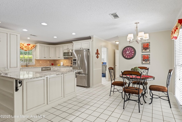 970 Raintree Dr, Alexander City, AL 35010 - kitchen featuring stainless steel appliances, decorative backsplash, crown molding, a textured ceiling, and a chandelier