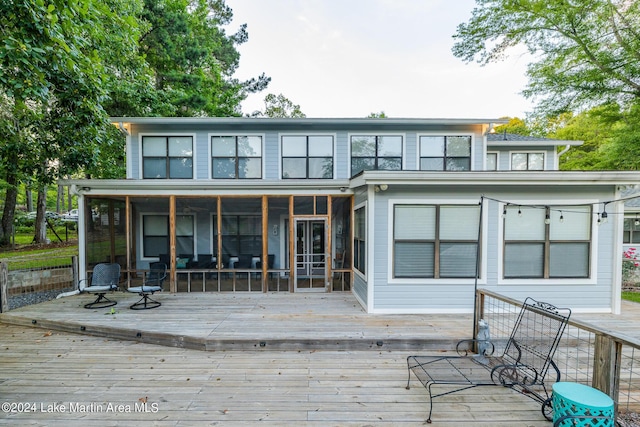 back of property with a deck and a sunroom