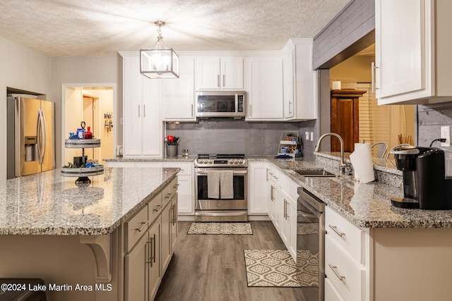 kitchen with white cabinets, sink, a breakfast bar area, decorative light fixtures, and stainless steel appliances