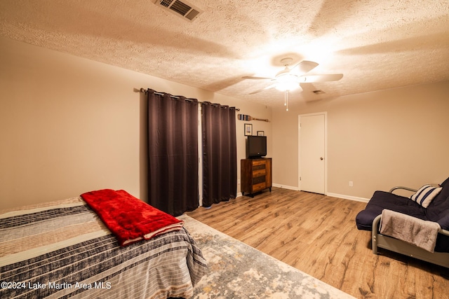 bedroom featuring ceiling fan, light hardwood / wood-style flooring, and a textured ceiling