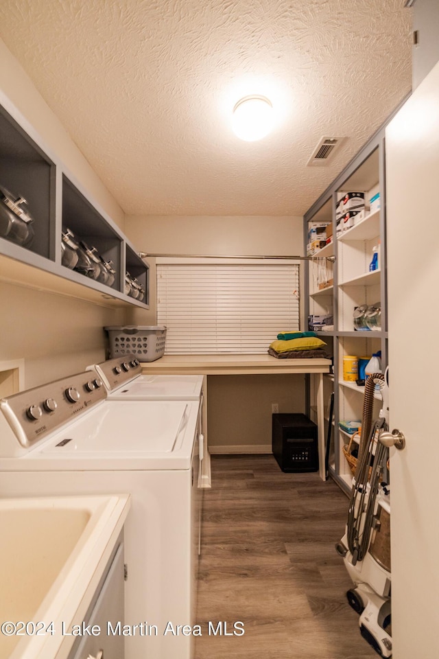 laundry room with washing machine and clothes dryer, dark wood-type flooring, and a textured ceiling