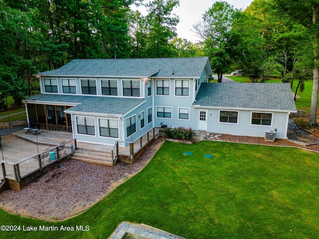 rear view of house with a sunroom, central AC unit, a deck, and a lawn