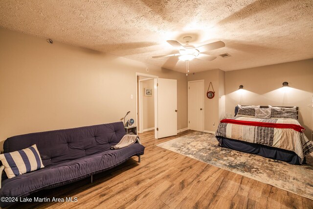 bedroom with a textured ceiling, light wood-type flooring, and ceiling fan