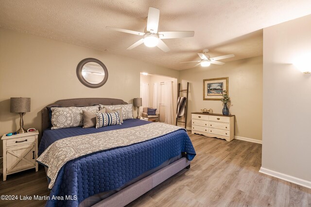 bedroom with ceiling fan, hardwood / wood-style floors, and a textured ceiling