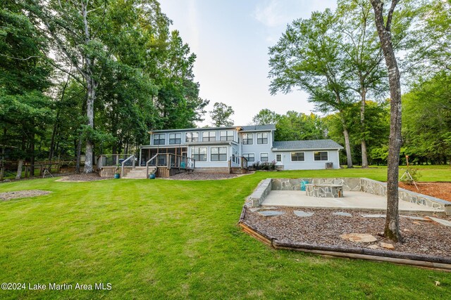 rear view of property featuring a sunroom, a yard, and a patio