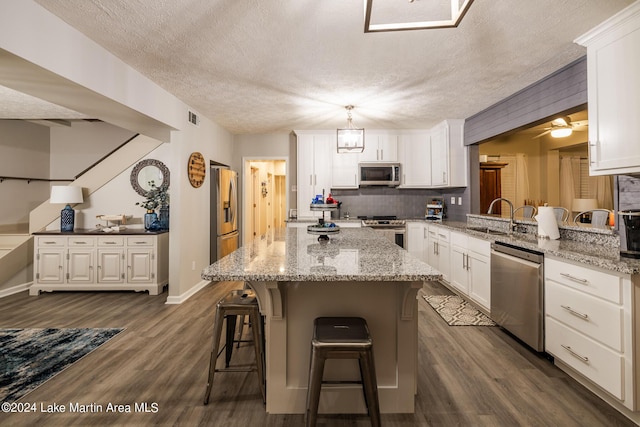 kitchen with dark hardwood / wood-style flooring, white cabinets, a textured ceiling, and appliances with stainless steel finishes