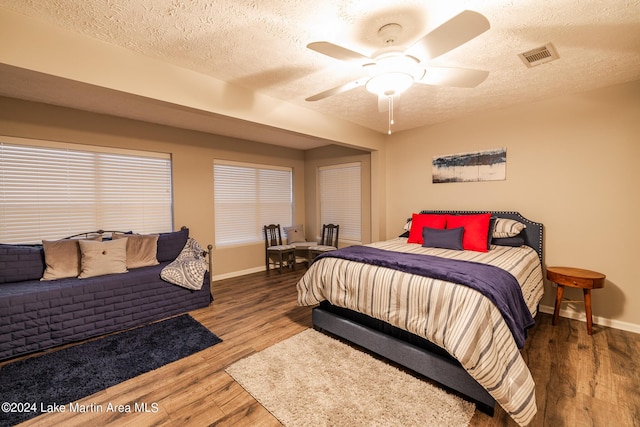 bedroom with ceiling fan, wood-type flooring, and a textured ceiling