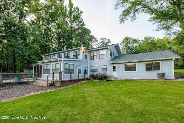 rear view of property featuring a sunroom, a lawn, and central AC