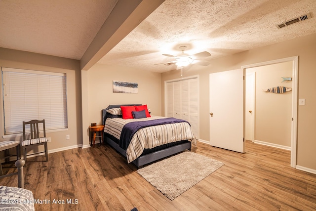 bedroom with hardwood / wood-style floors, ceiling fan, a textured ceiling, and a closet