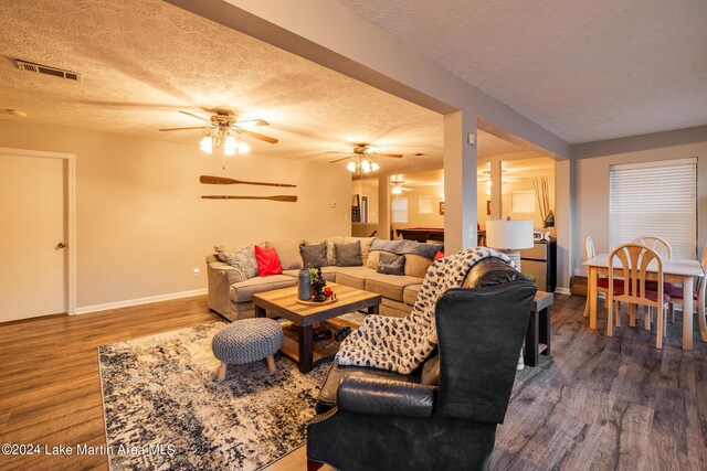 living room featuring ceiling fan, dark hardwood / wood-style flooring, and a textured ceiling