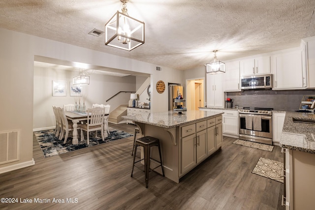 kitchen featuring decorative light fixtures, a center island, stainless steel appliances, and dark wood-type flooring