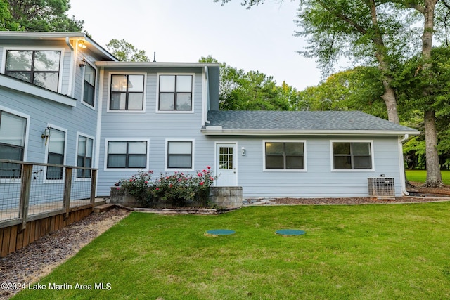 rear view of property with a yard and central air condition unit