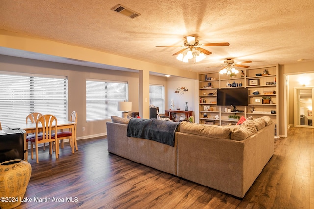 living room featuring ceiling fan, dark hardwood / wood-style flooring, and a textured ceiling