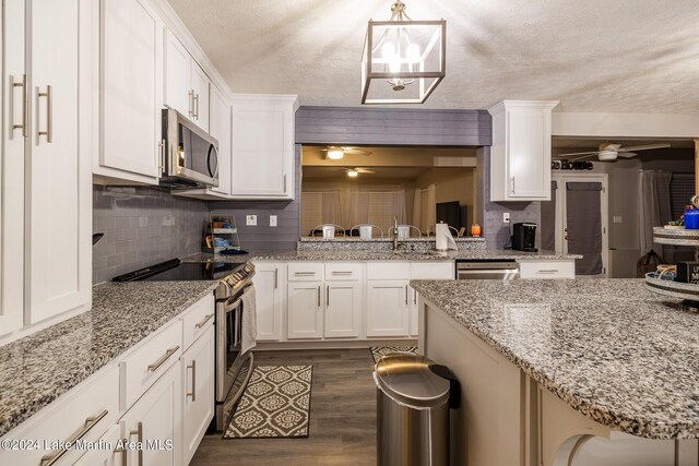 kitchen featuring decorative light fixtures, dark hardwood / wood-style flooring, white cabinetry, and appliances with stainless steel finishes