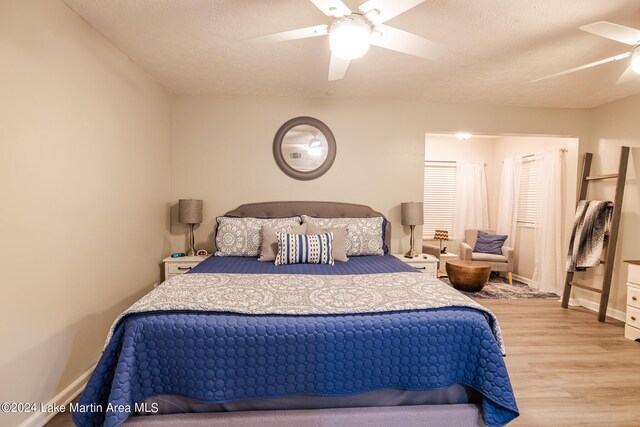 bedroom with ceiling fan, light hardwood / wood-style floors, and a textured ceiling