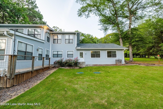 rear view of property with a lawn and central air condition unit